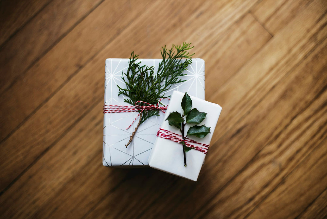 Schlicht verpackte Geschenke aus Naturkarton mit zwei grünen Blättern